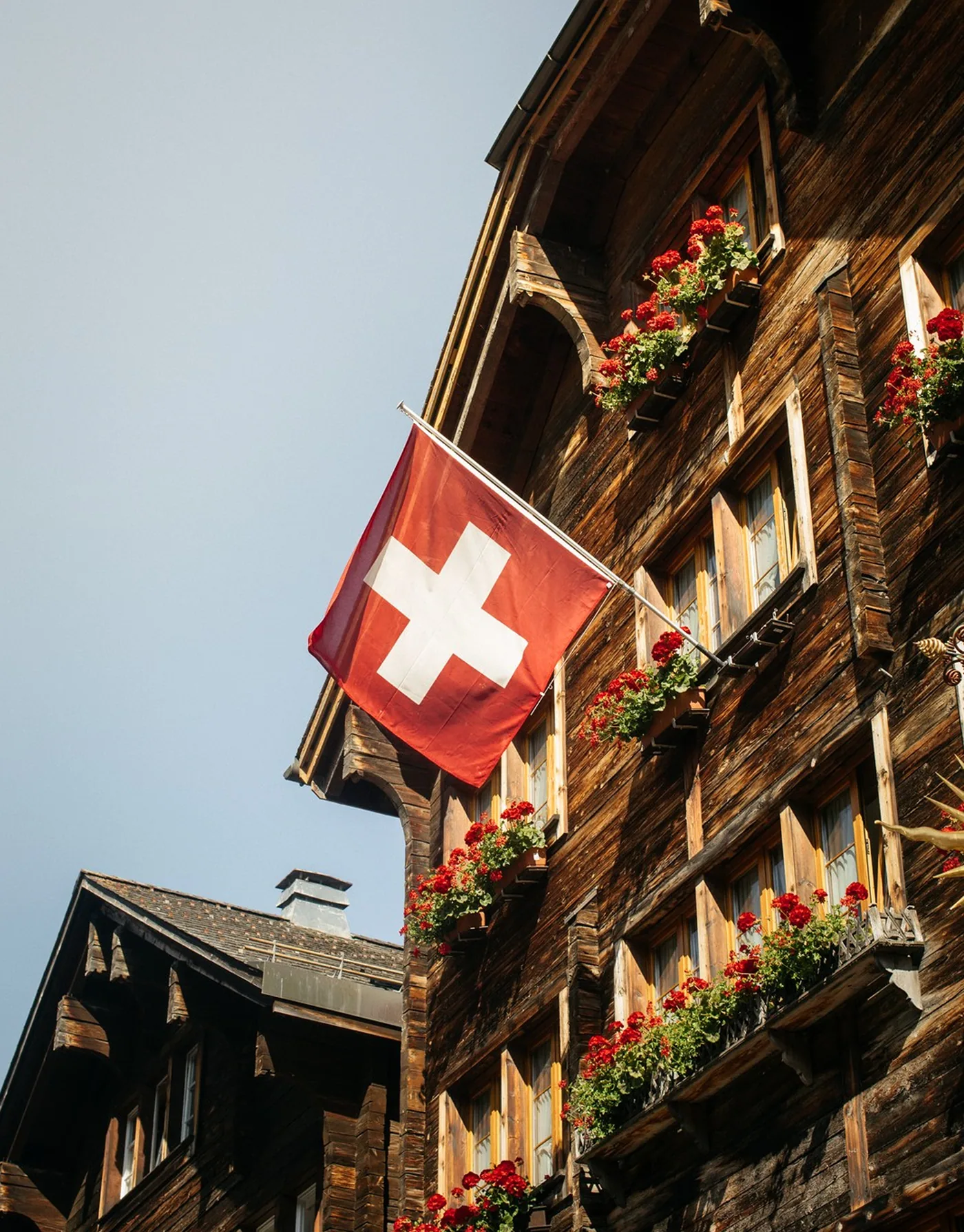 Swiss flag on a traditional timber chalet with red geraniums
